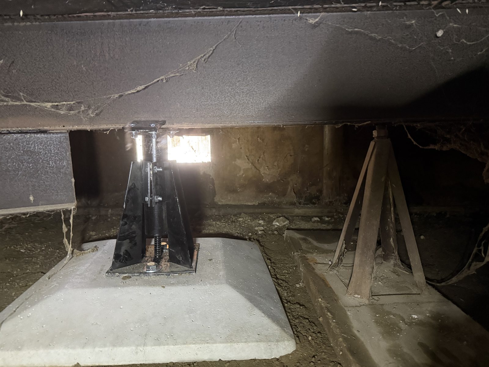 A new engineered pier and concrete footing installed beside the manufactured home's original support stand.